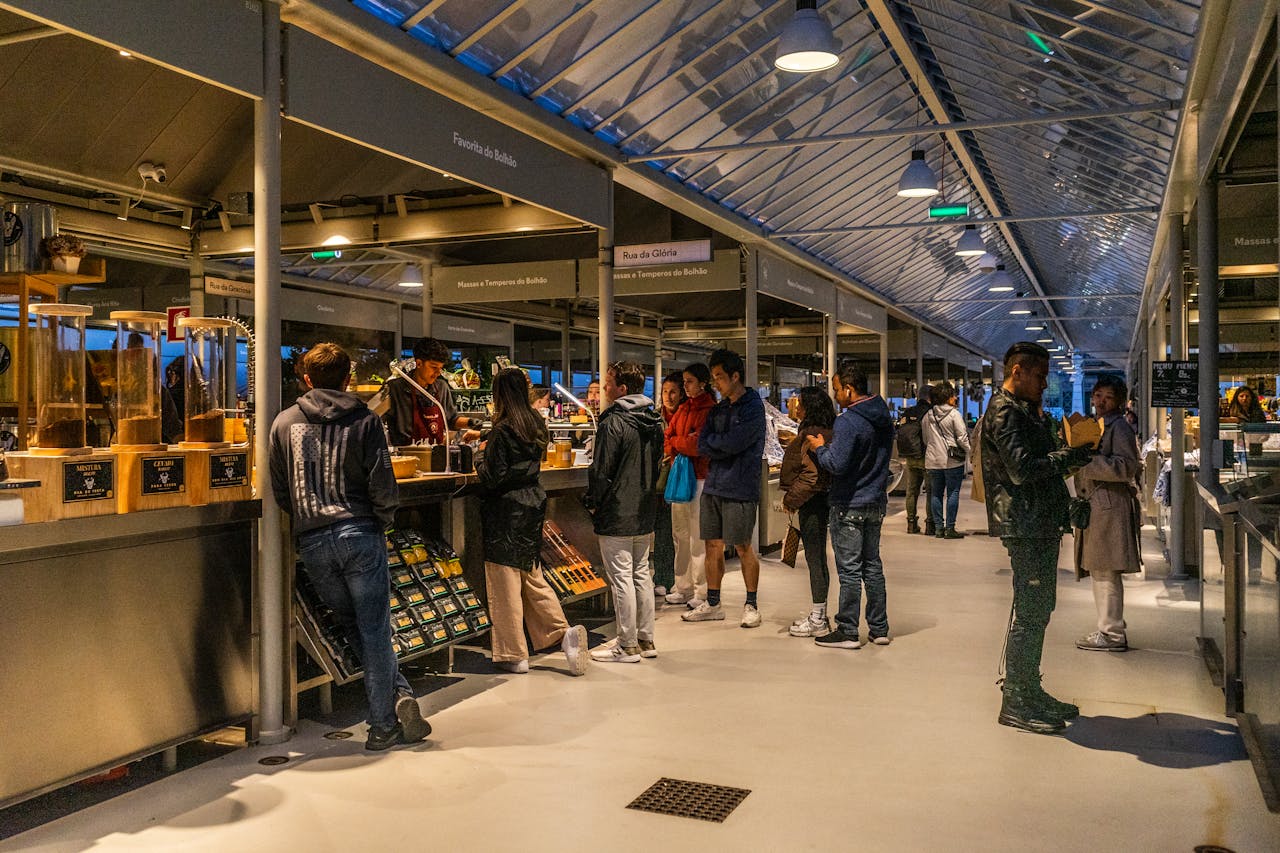 People shopping at an indoor market in Porto, Portugal. Vibrant atmosphere with diverse stalls.