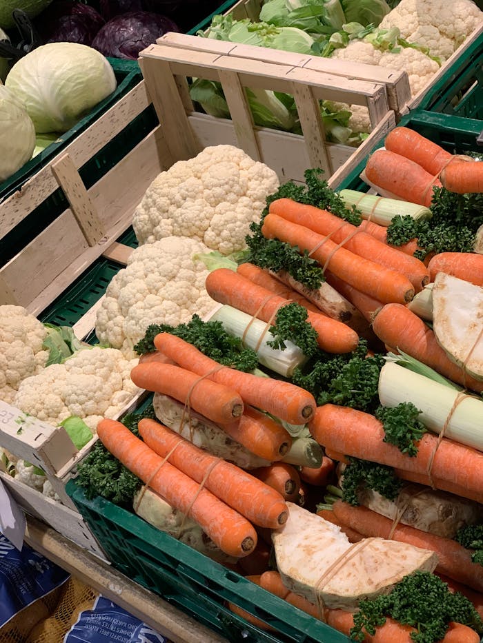 Vibrant display of fresh carrots, cauliflower, and celery at an indoor market, ideal for healthy lifestyle themes.